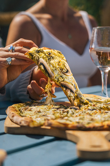 Person-picking-up-pizza-slice-with-wine-glass